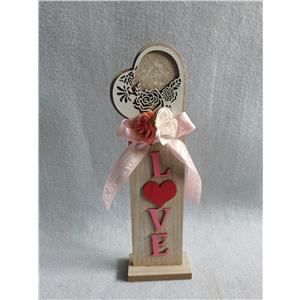 Corazón de madera sobre soporte con palabra LOVE